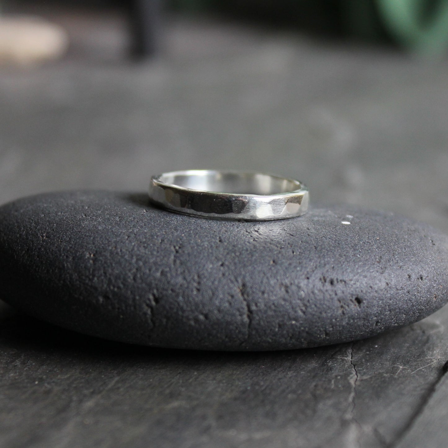 A handmade sterling silver 3mm wide ring with rounded edges and a hammered finish. 
