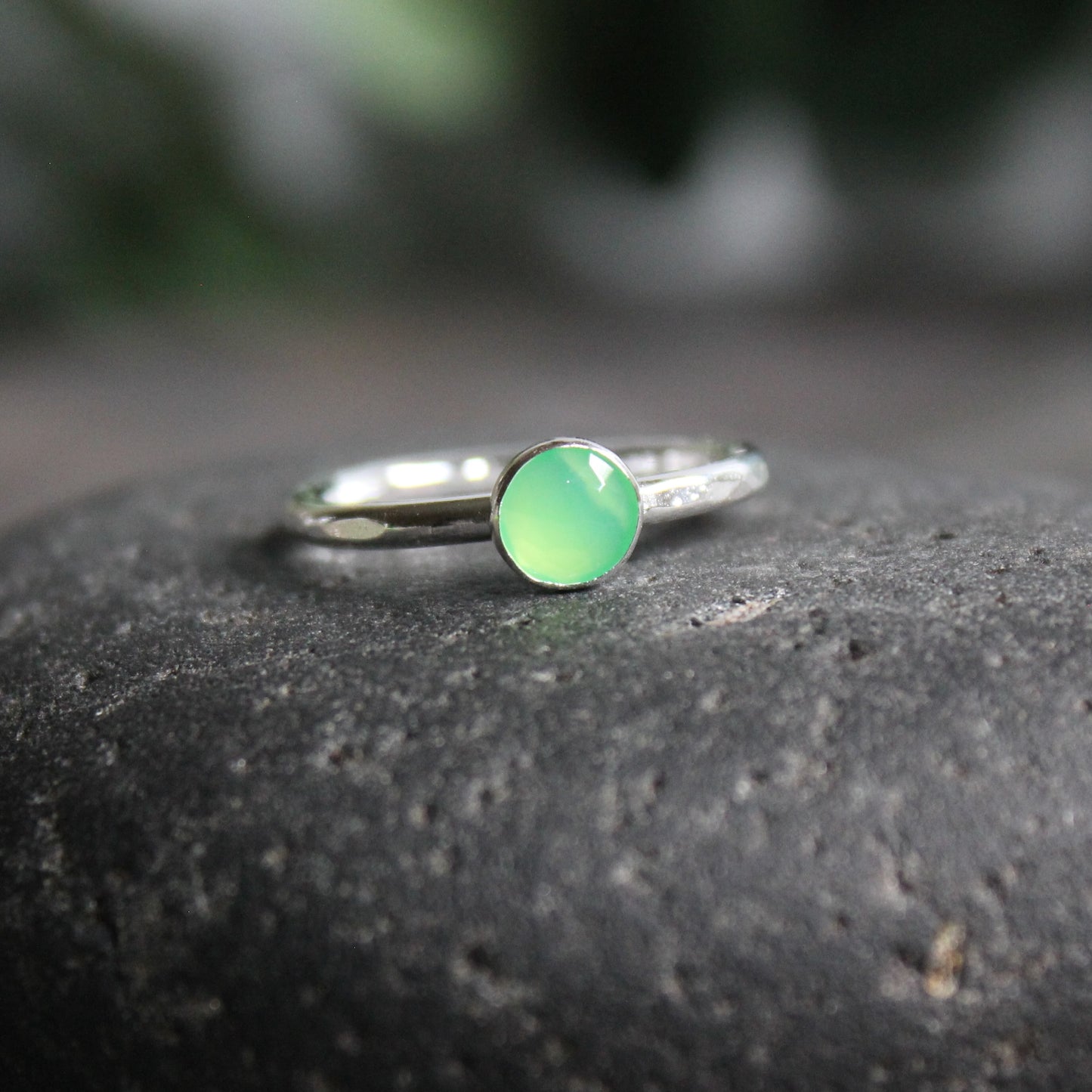 A 6mm rose cut round chrysoprase cabochon set in a sterling silver bezel setting on a sturdy silver band. 