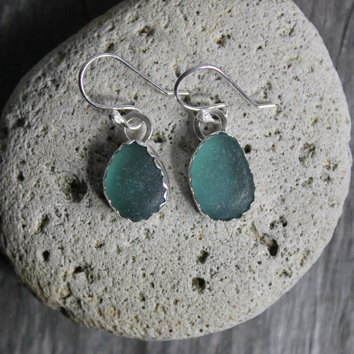 Dark teal sea glass set in a fine and sterling silver scalloped bezel setting and attached to handmade ear wires.  