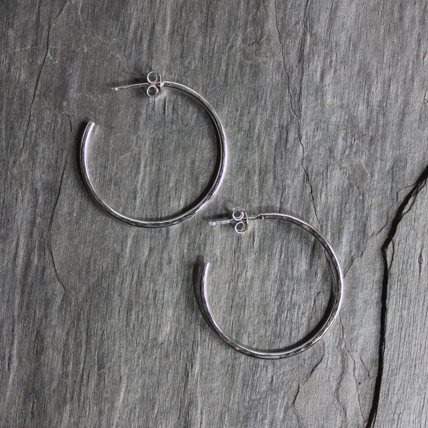 Handmade hammered sterling silver classic hoop earrings on sterling silver posts with earring nuts that are approximately 1 1/4 inch diameter. 