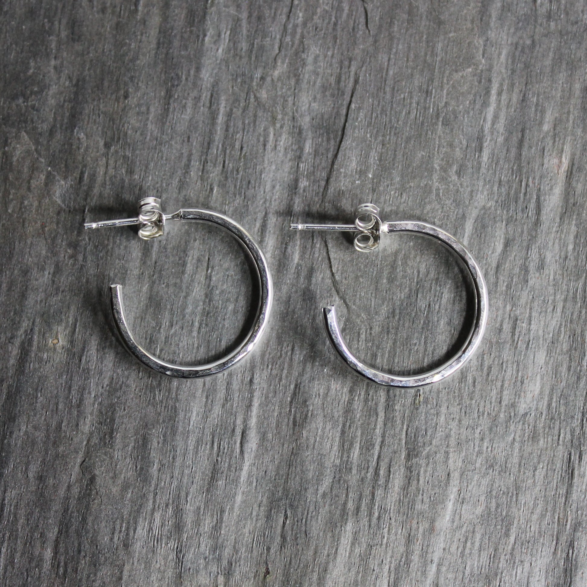 Sterling silver hammered hoops on posts approximately 3/4" in diameter with a bright finish. 