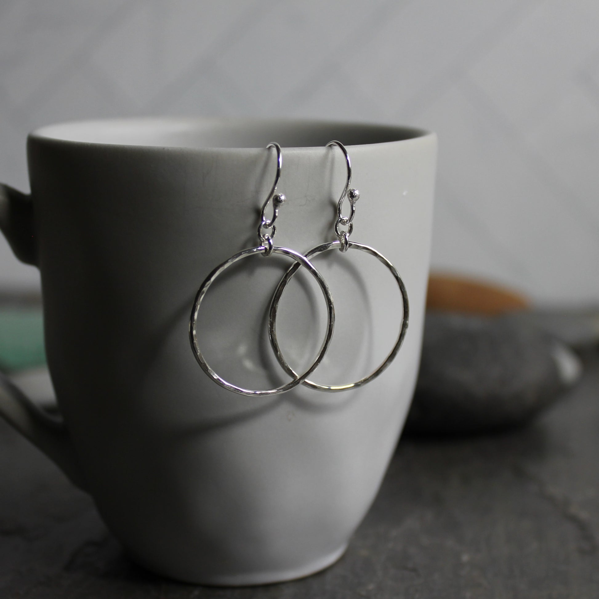 These earrings have 1 inch diameter hammered sterling silver circles attached to handmade ear wires.