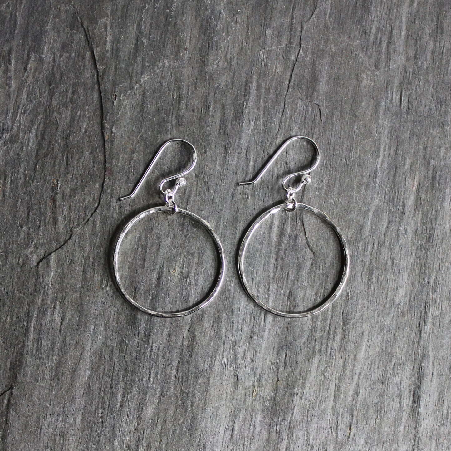 These earrings have 1 inch diameter hammered sterling silver circles attached to handmade ear wires.