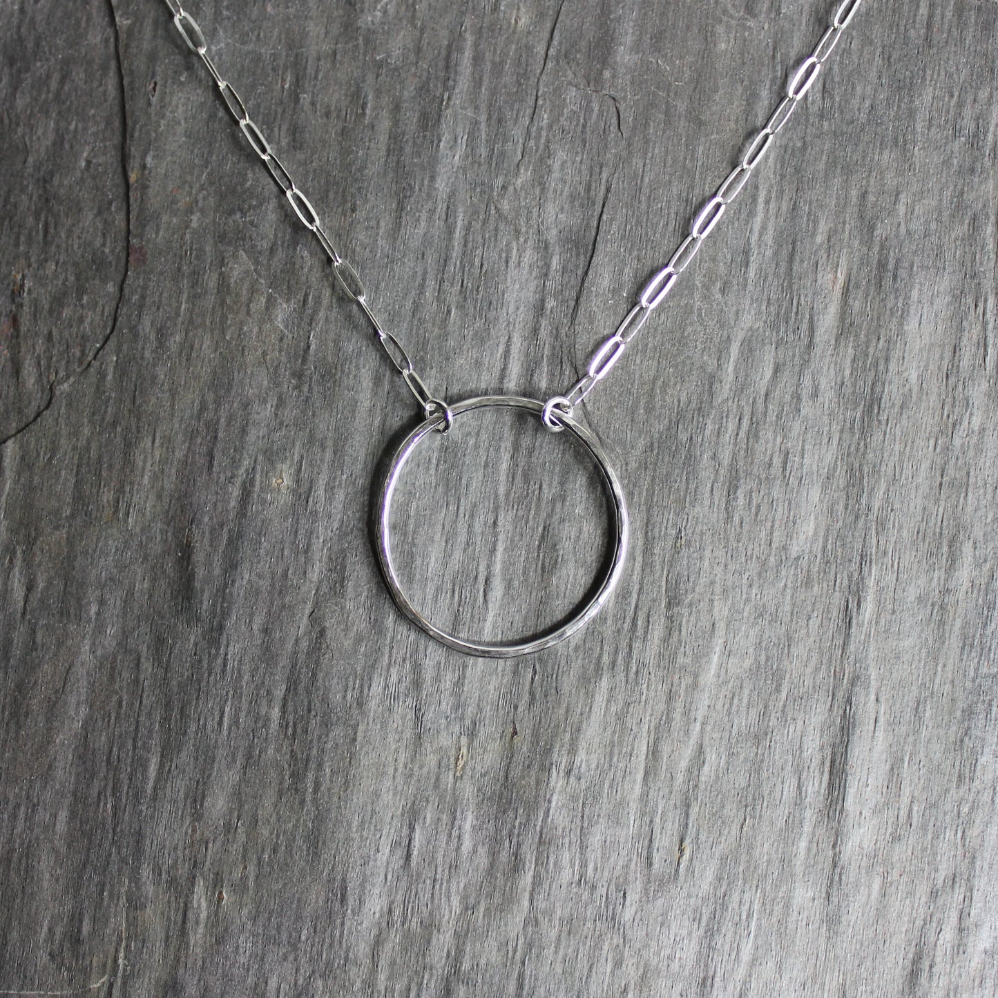 A 1 inch diameter sterling silver hammered circle attached to sterling silver chain to make an elegantly simple necklace.