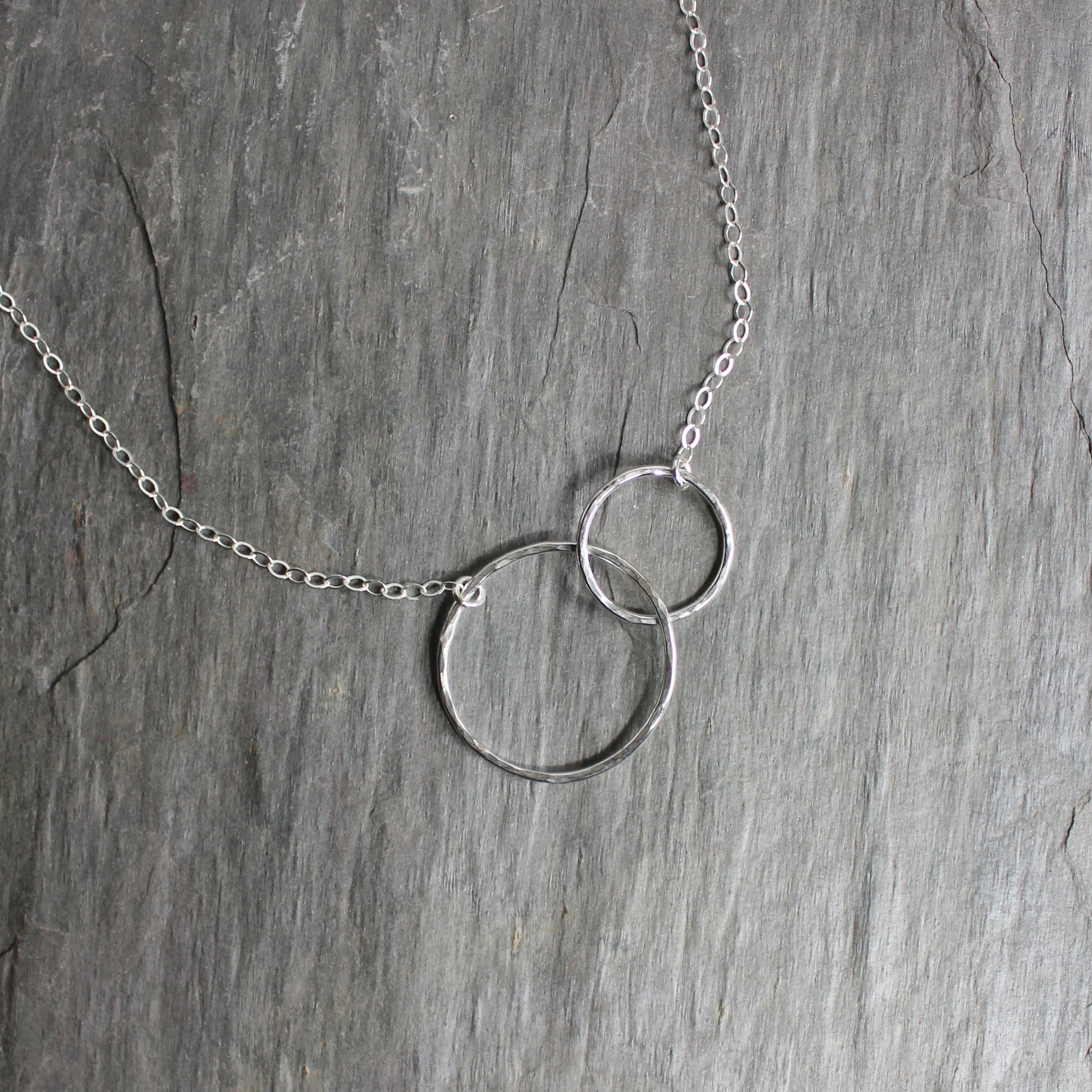 A one inch hammered circle and a 1/2 inch hammered circle interlocking and attached to sterling silver chain to make a elegant necklace.