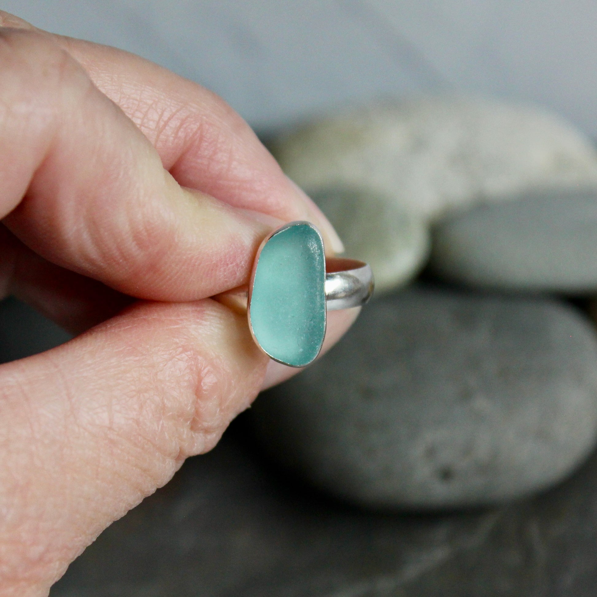 An oblong piece of aqua blue sea glass set in a fine and sterling silver bezel setting on a sturdy silver band. 
