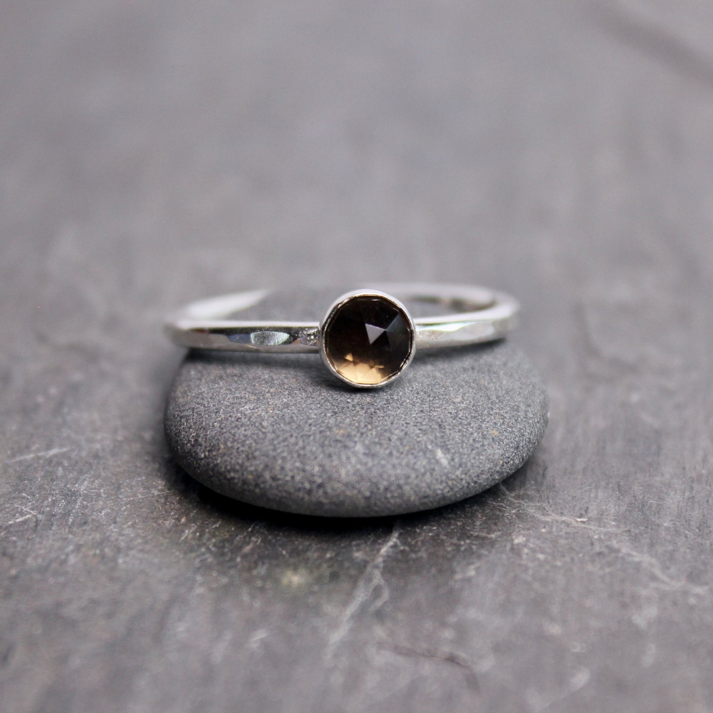 Silver ring with a black gemstone on a gray stone surface
