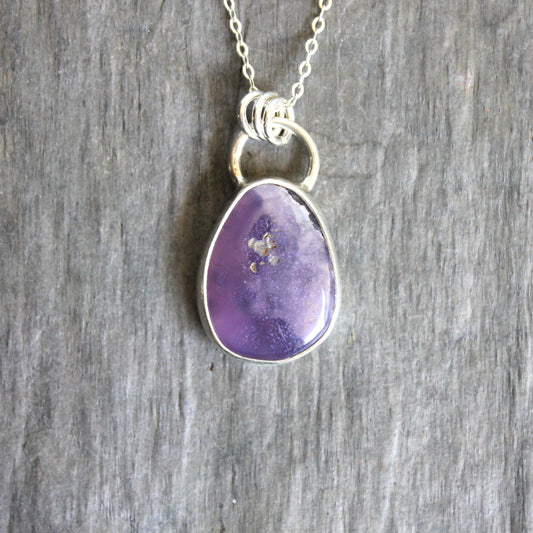 Purple teardrop pendant on a silver chain against a wooden background. A holley blue agate cabochon set in a fine and sterling silver bezel setting on a sturdy silver chain.
