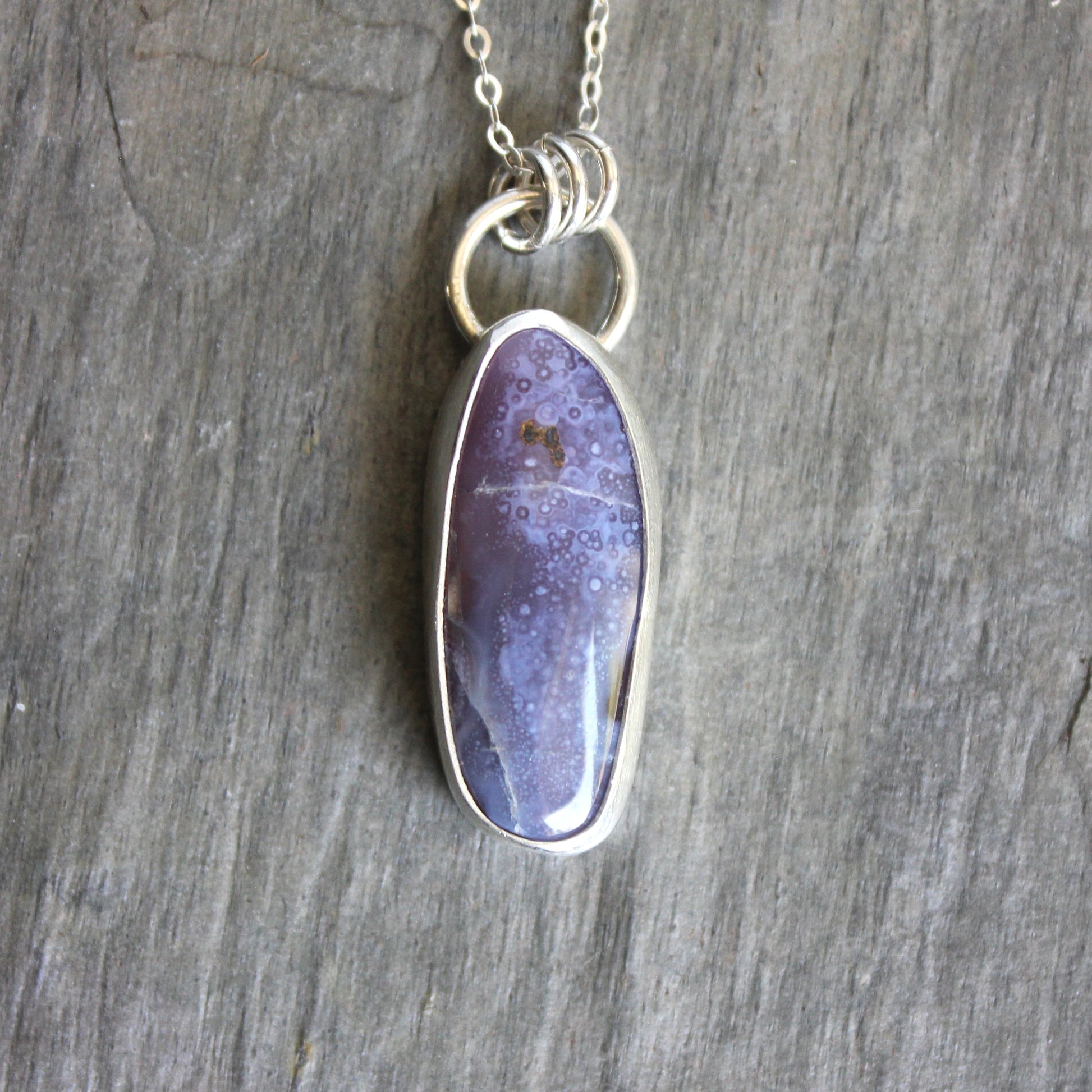 A long holley blue agate cabochon set in a fine and sterling silver bezel setting on a sturdy silver chain.