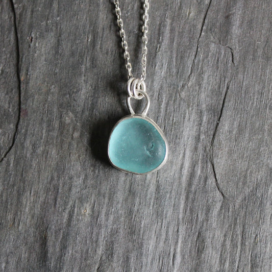 This necklace has a piece of teal sea glass set in a fine and sterling silver bezel setting with a sterling silver chain.