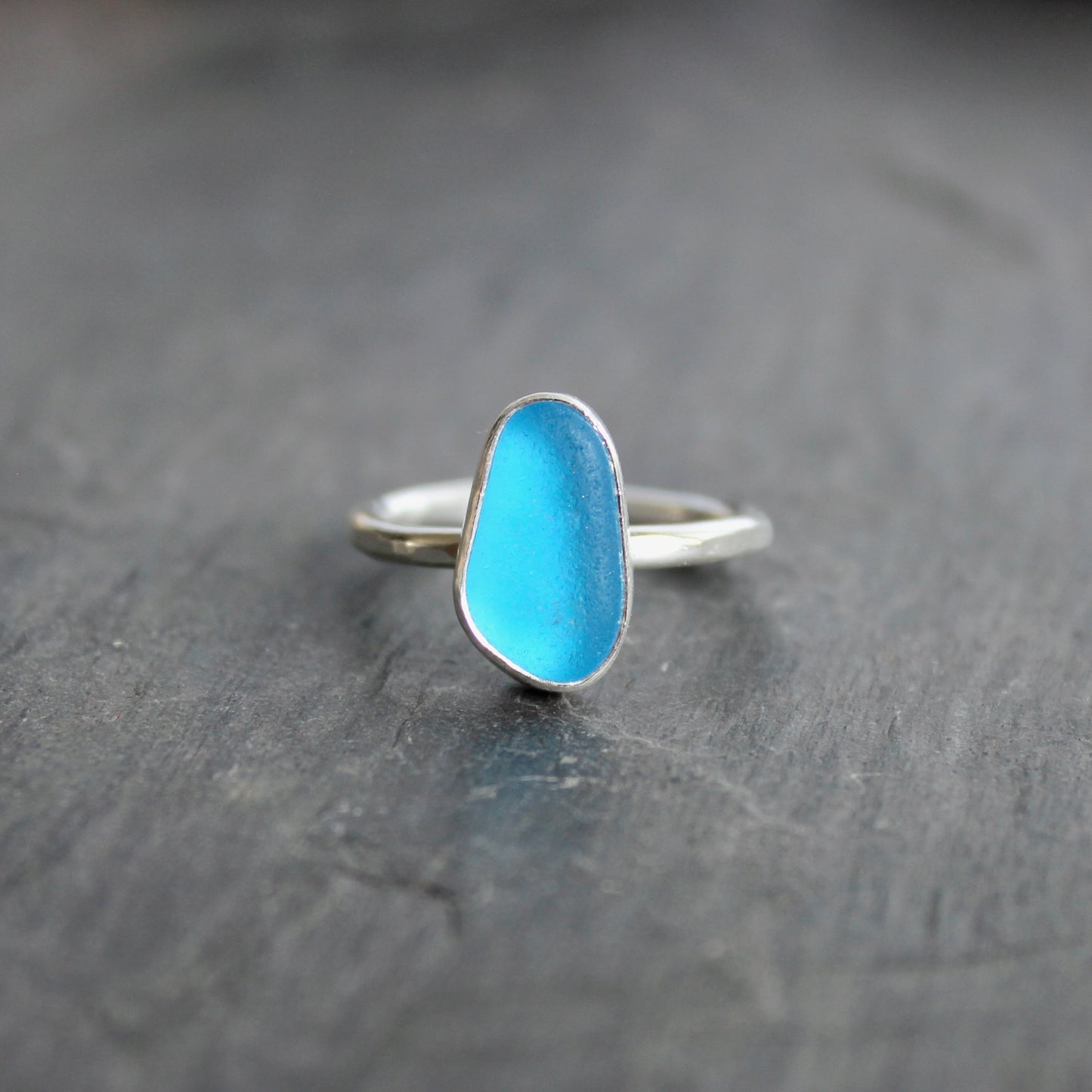 This ring has a piece of electric turquoise blue sea glass that is set in a fine and sterling silver bezel setting on a sturdy silver band. Size 7 3/4 Handmade by Barb Macy in Corvallis, OR.