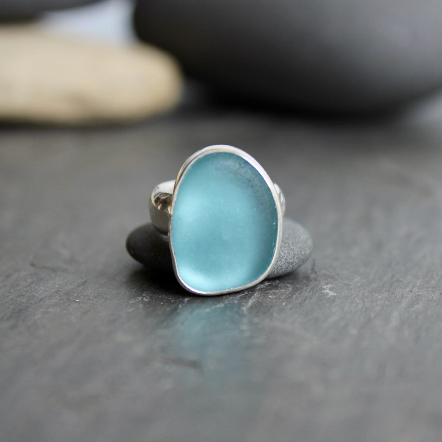 This ring has a large piece of aqua turquoise blue sea glass that is set in a fine and sterling silver bezel setting on a sturdy wide hammered band. Size 4 1/2 Handmade by Barb Macy in Corvallis, Oregon.