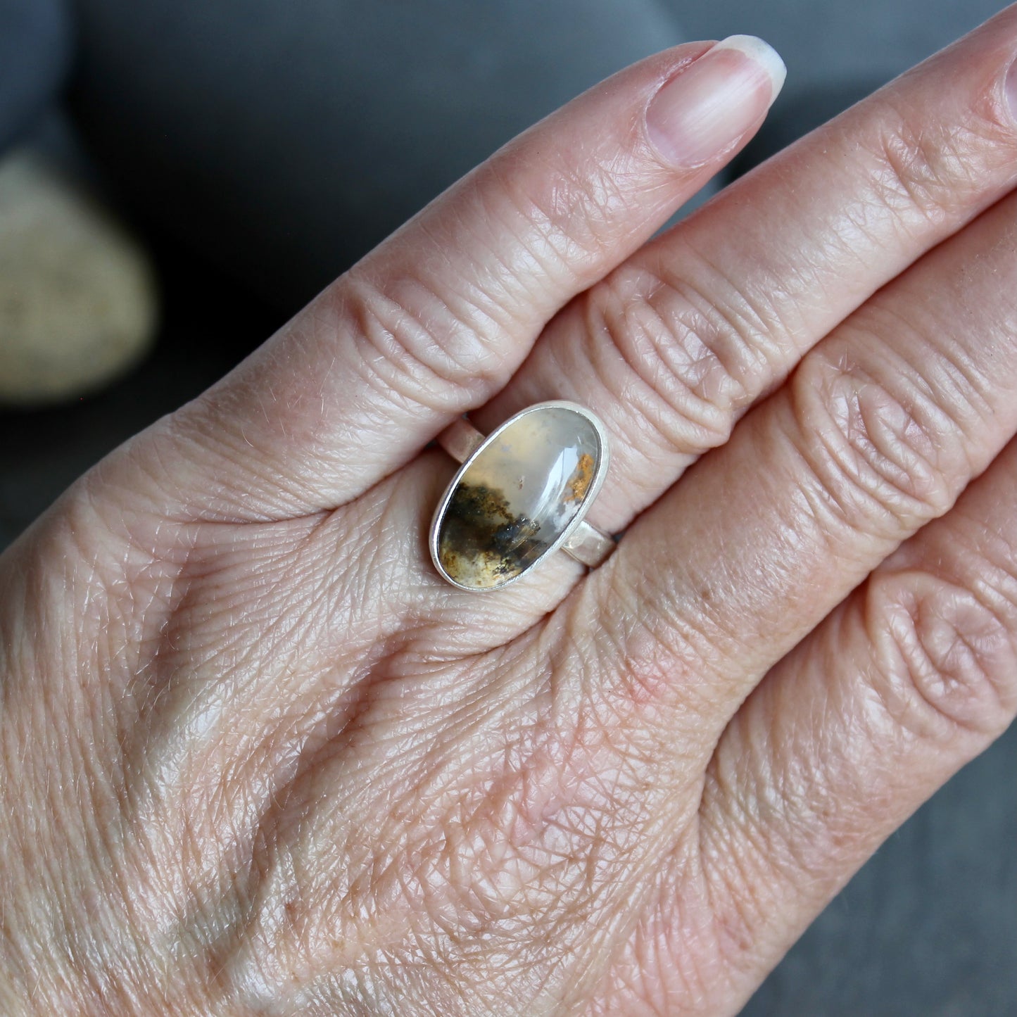This ring has an Oregon Graveyard Point plume agate that is set in a fine and sterling silver bezel setting on a sturdy hammered band. Size 7 Handmade by Will Macy in Corvallis, Oregon.