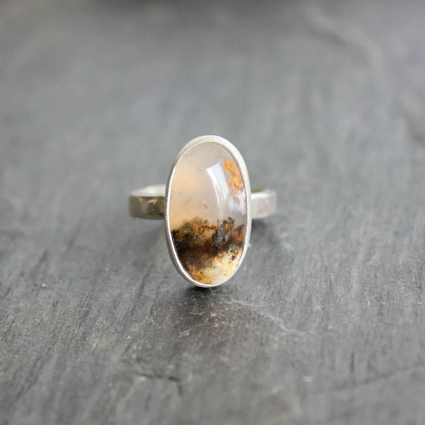 This ring has an Oregon Graveyard Point plume agate that is set in a fine and sterling silver bezel setting on a sturdy hammered band. Size 7 Handmade by Will Macy in Corvallis, Oregon.