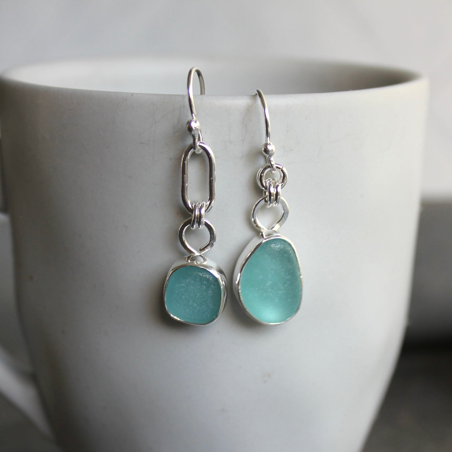 Mismatched Turquoise Blue Sea Glass dangly earrings. They are set in a sterling and fine silver bezel setting and are on sterling silver ear wires.