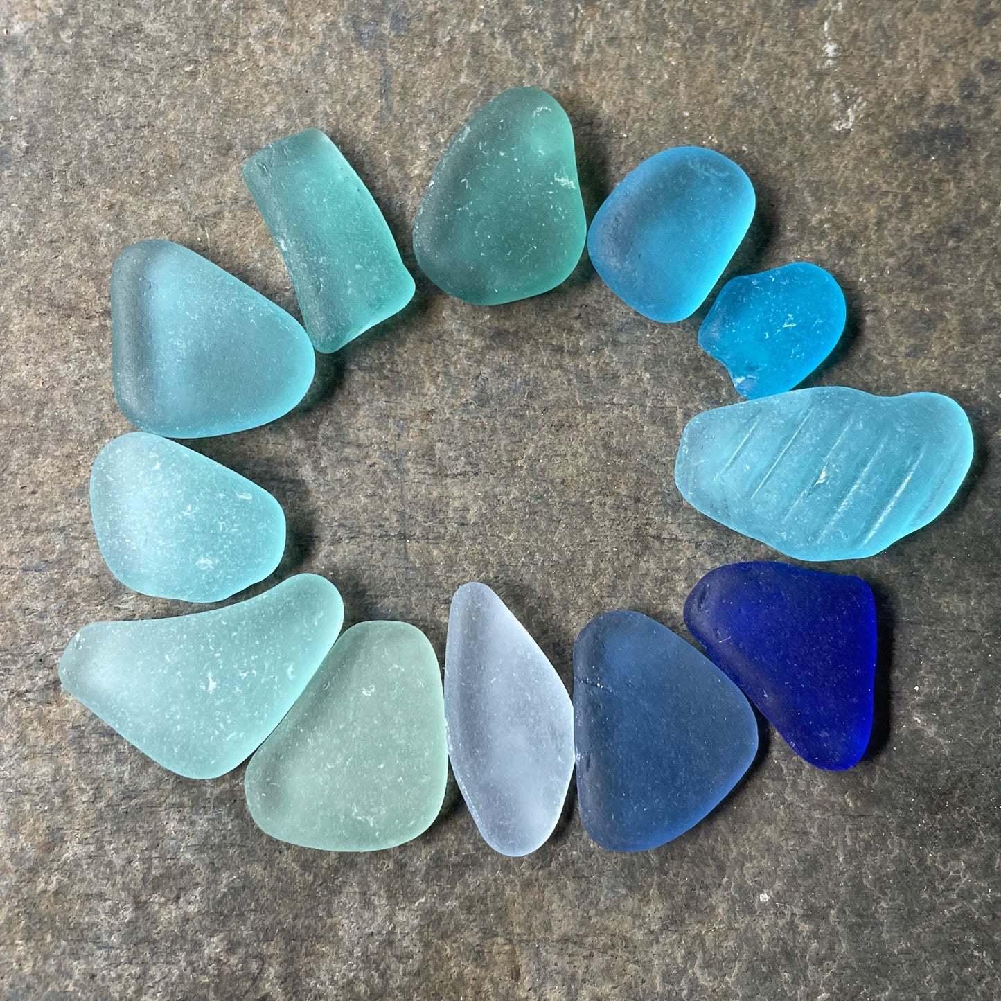 A collection of sea glass in shades of blue including cobalt blue, dark blue, cornflower, aqua and turquoise.