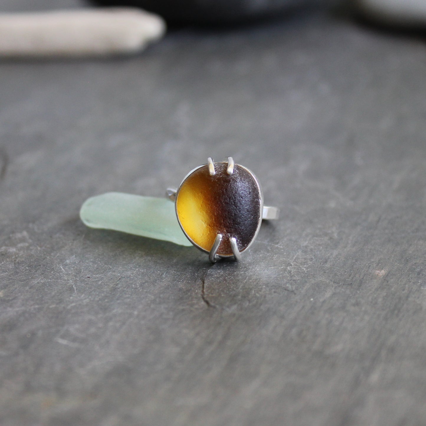 This ring has a piece of amber brown Seaham (UK) sea glass that is set in a fine and sterling silver bezel and soldered to a sturdy sterling silver band.