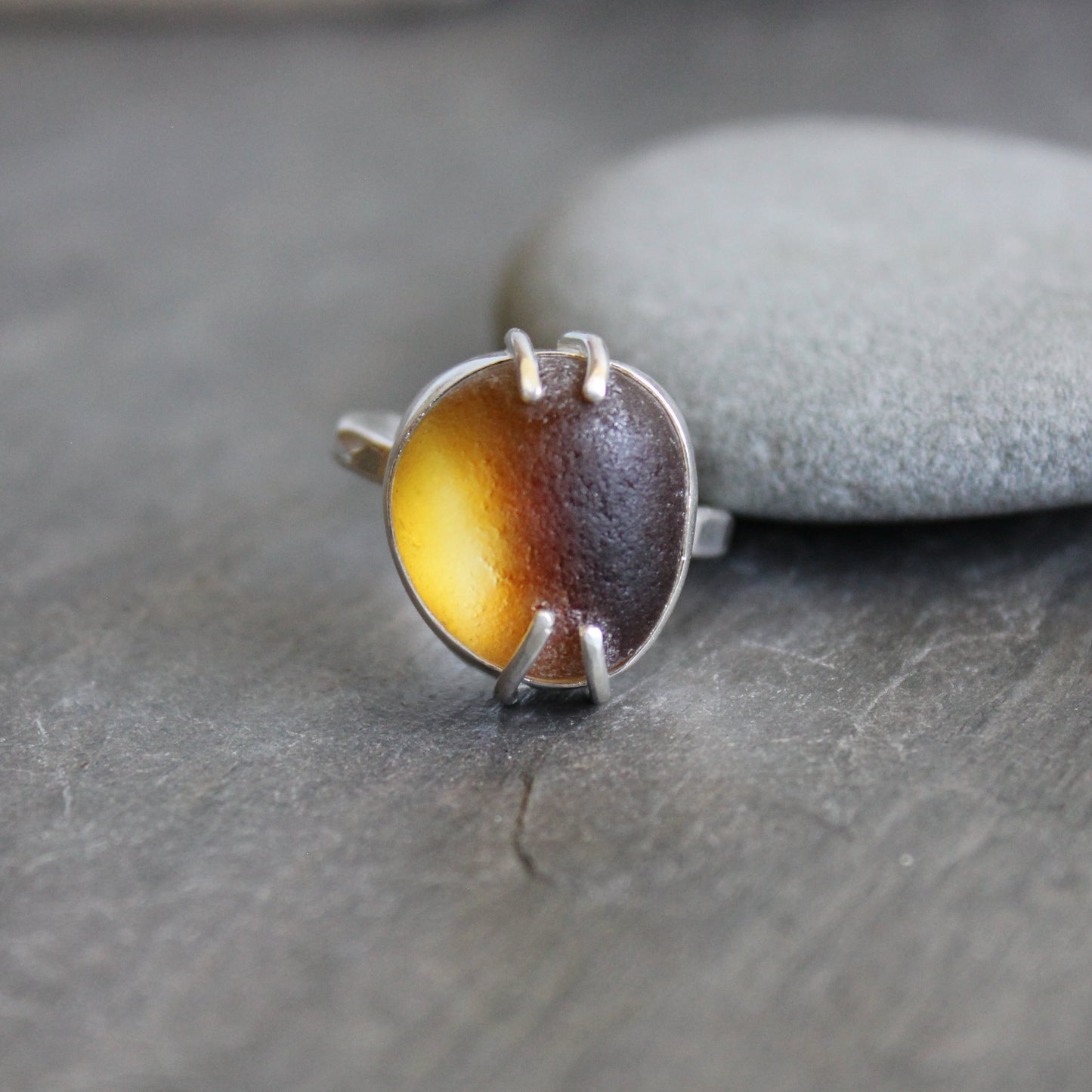 This ring has a piece of amber brown Seaham (UK) sea glass that is set in a fine and sterling silver bezel and soldered to a sturdy sterling silver band.