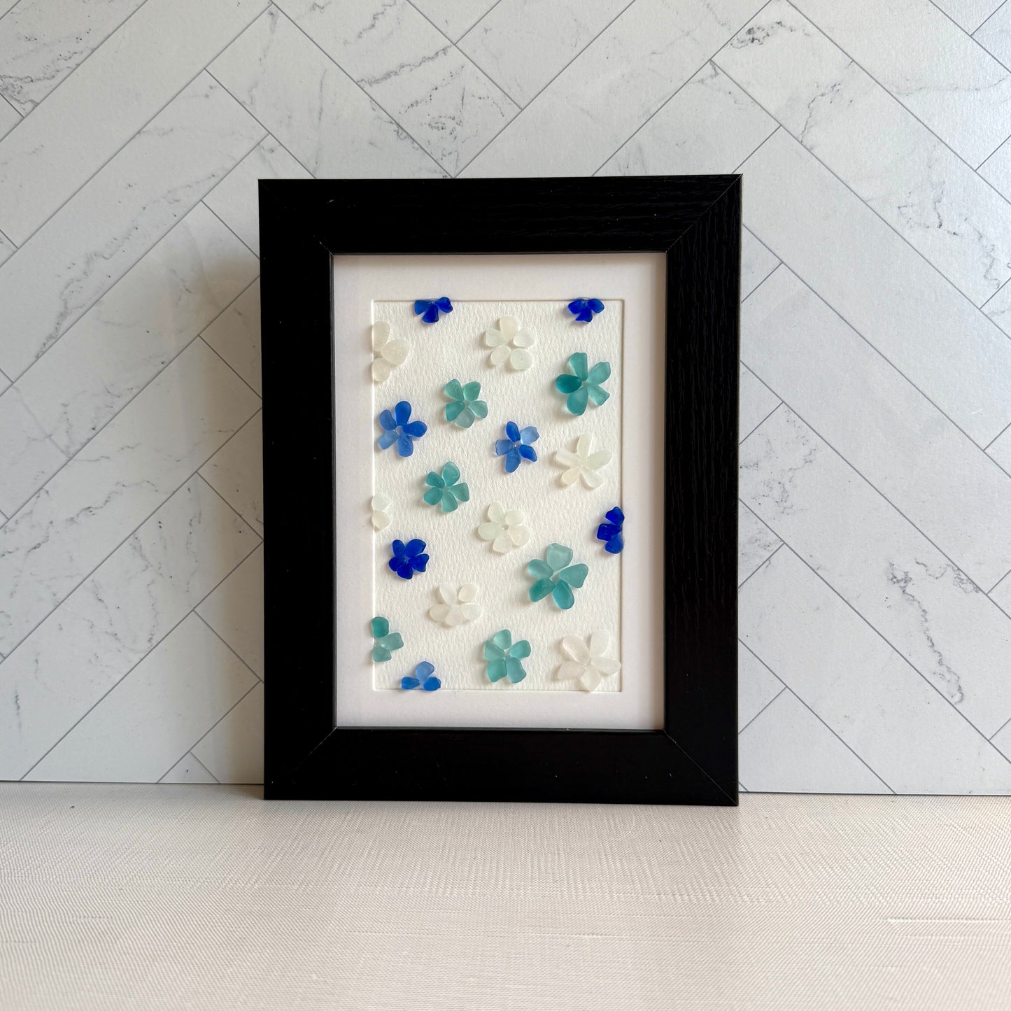 Framed artwork with colorful flower patterns on a marble background