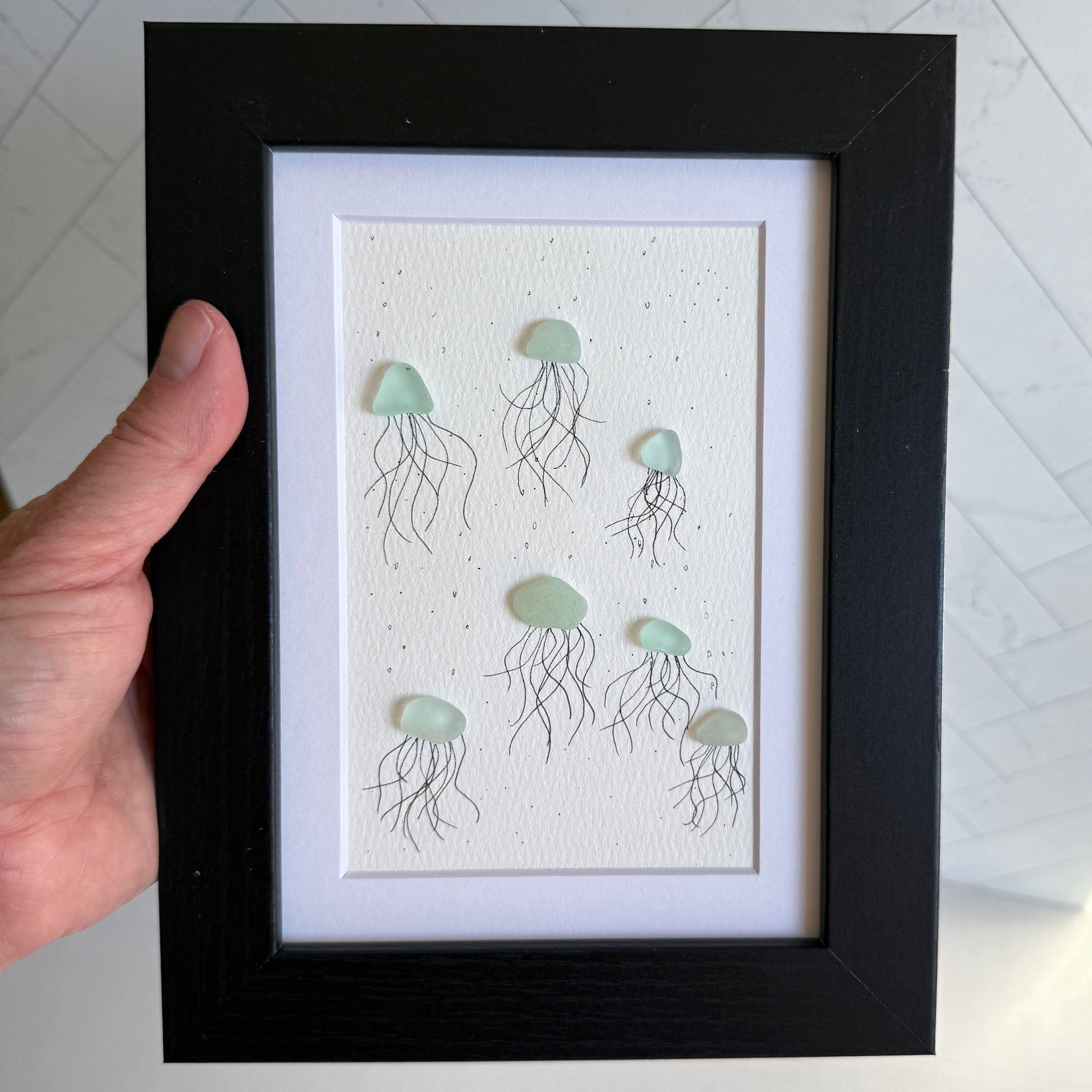 Framed artwork of sea glass jellyfish on a textured white background