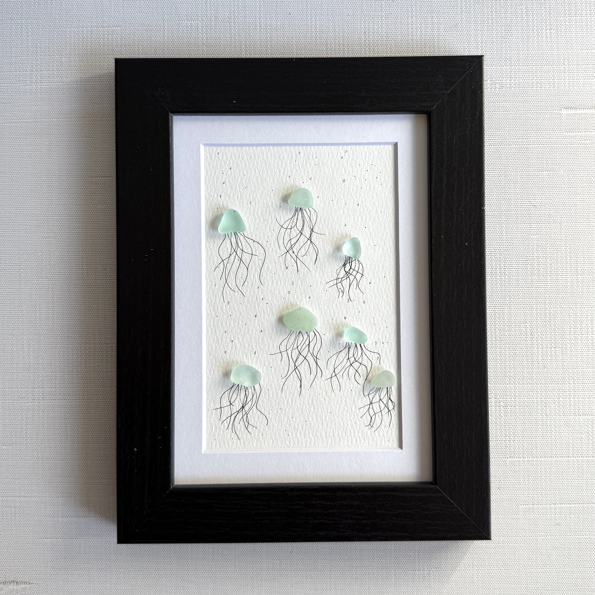 Framed artwork of sea glass jellyfish on a textured white background