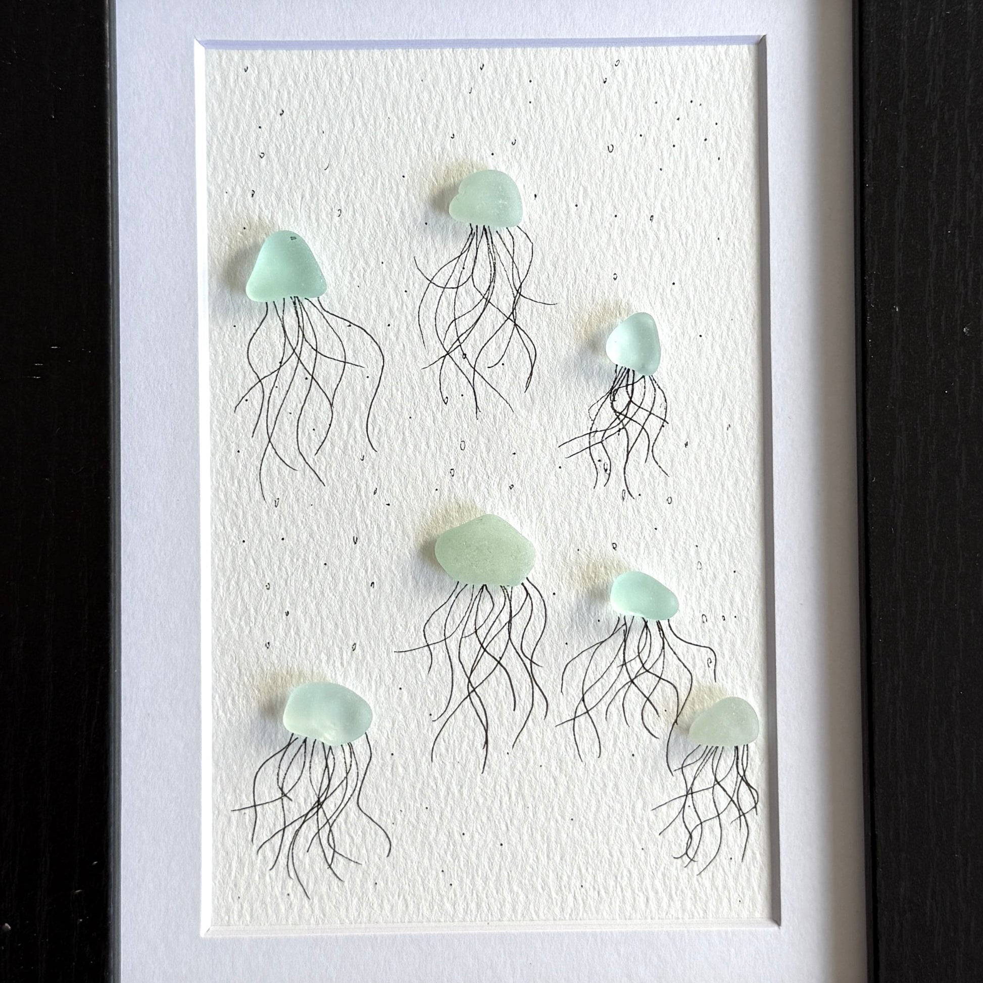 Framed artwork close-up of sea glass jellyfish on a textured white background
