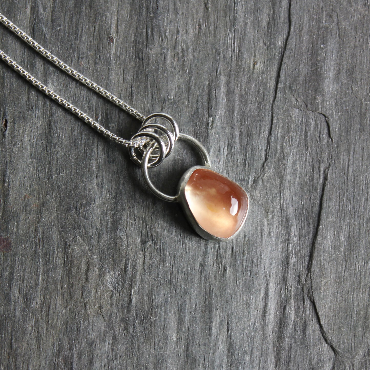 This small 10mm x 12mm peach Oregon sunstone is set in a fine & sterling silver bezel setting on an 18" chain. 