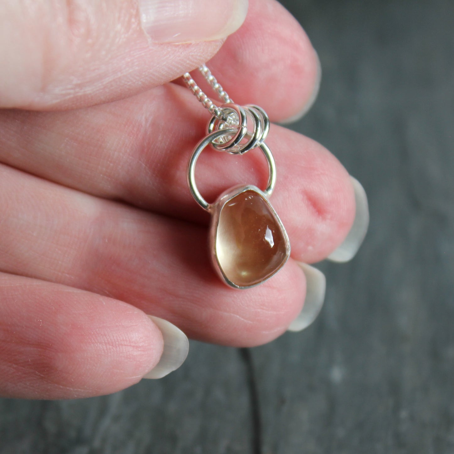 This small 10mm x 12mm peach Oregon sunstone is set in a fine & sterling silver bezel setting on an 18" chain. 