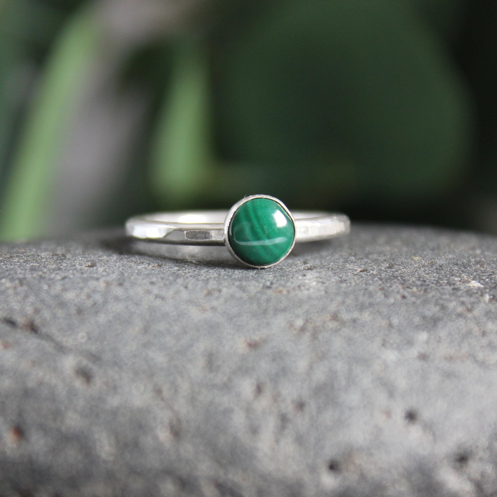 A 6mm round malachite cabochon set in a sterling silver bezel cup on a sturdy silver band. 