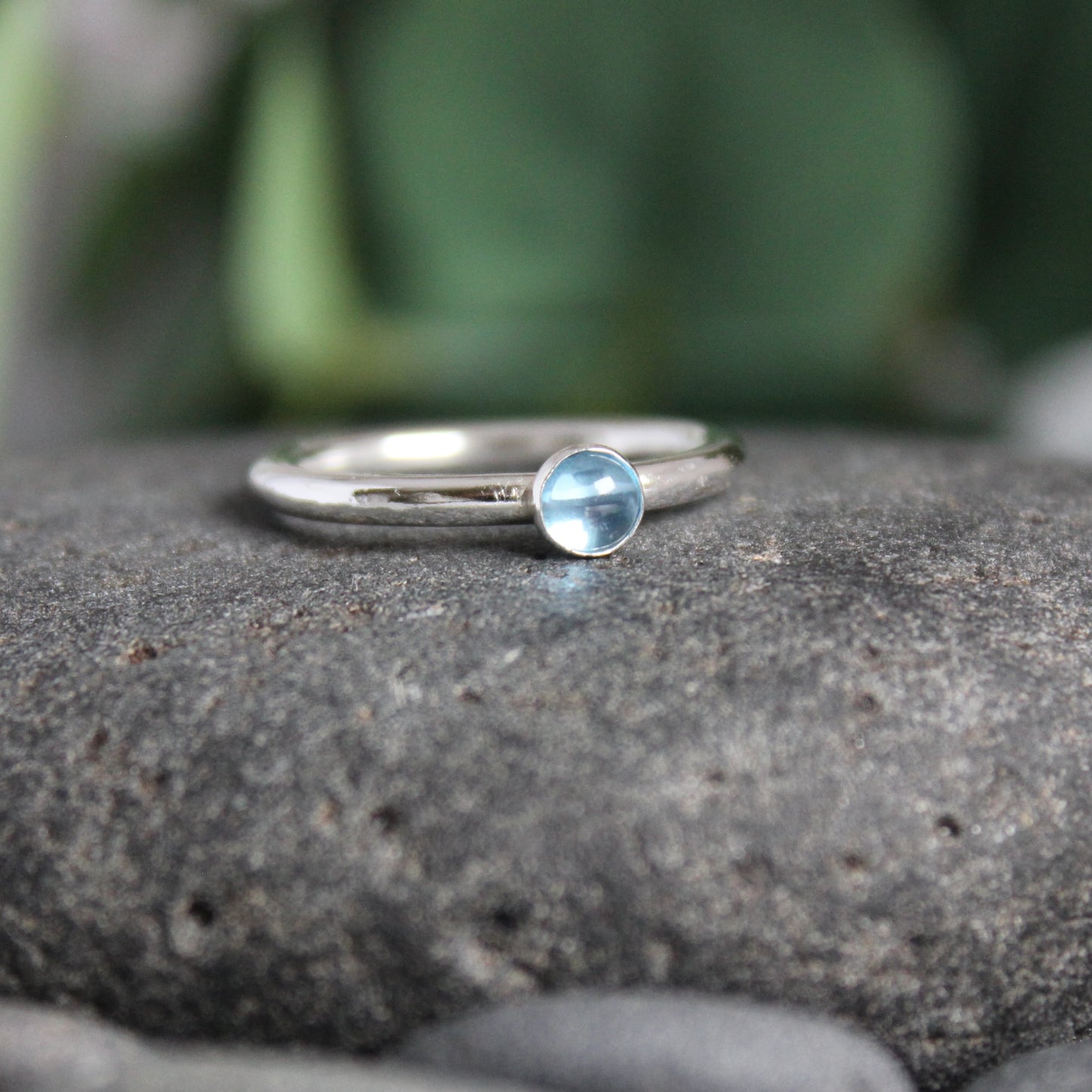 A 4mm round blue topaz cabochon set in a handmade sterling silver bezel setting on a sturdy silver band. 