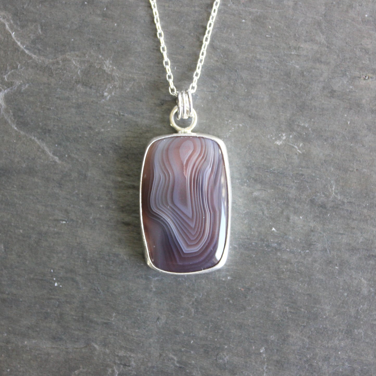 Necklace with a pendant featuring a rectangular botswana agate on a gray background