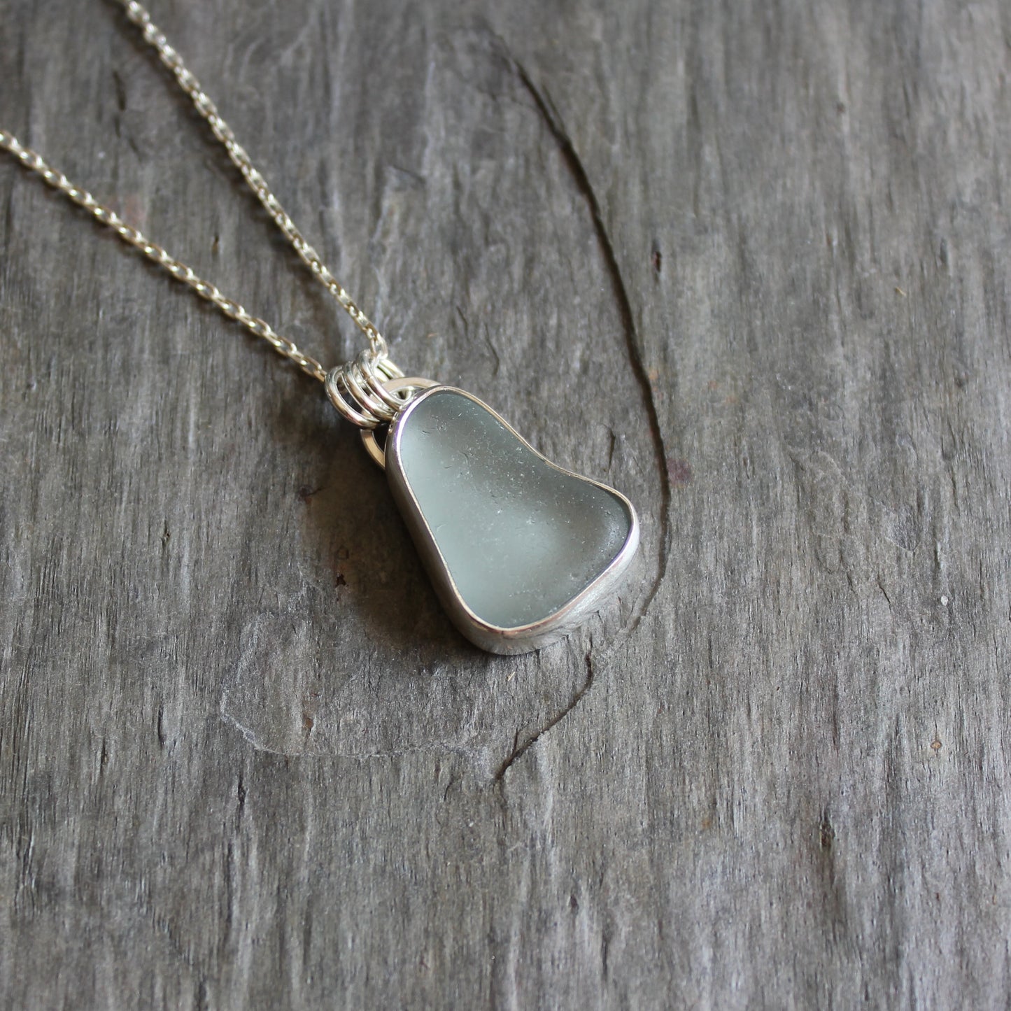 This pendant has a chunky piece of gray sea glass and it is set in a fine and sterling silver bezel setting with an 18" chain.