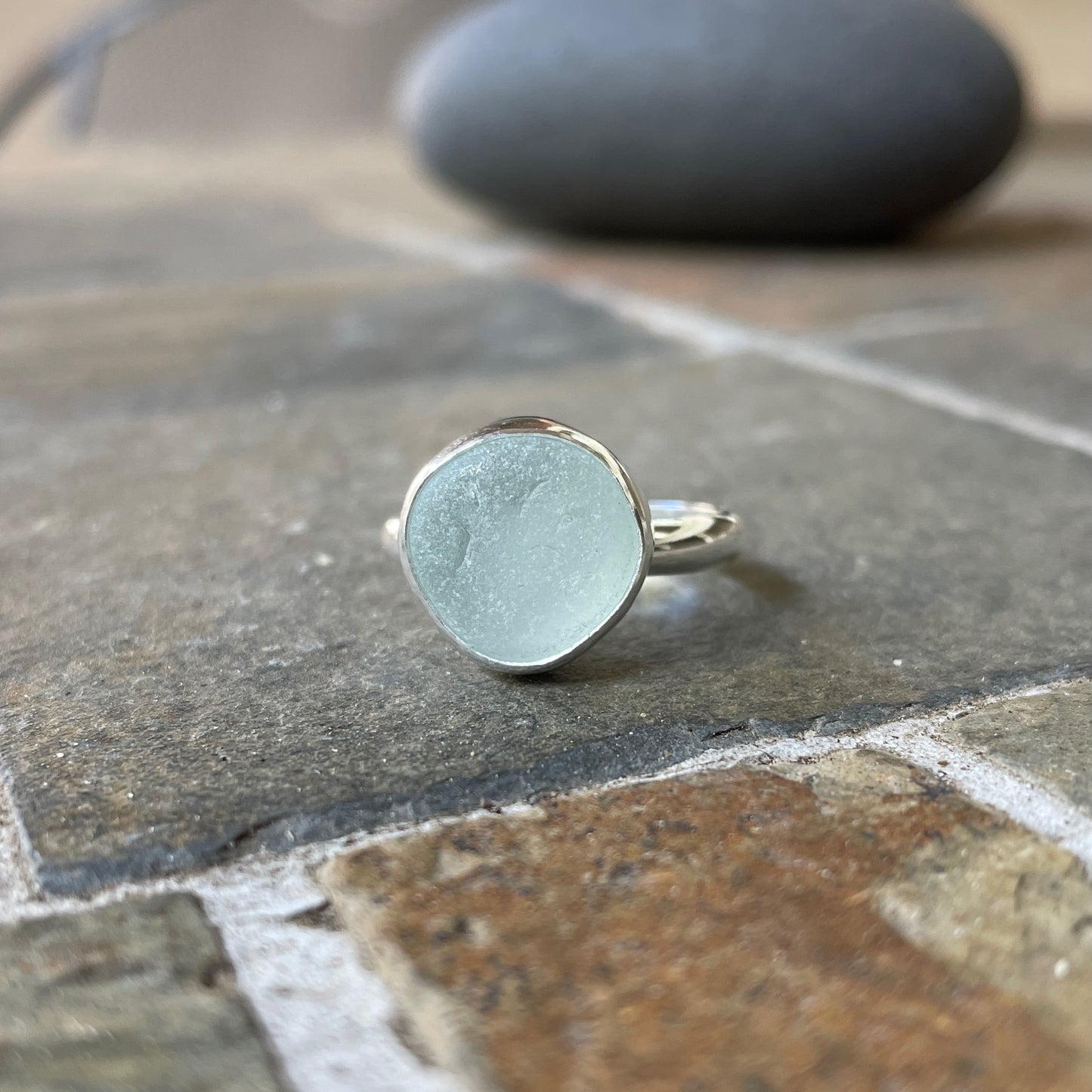 This is a chunky round piece of white sea glass set in a fine and sterling silver bezel setting with a hammered silver band.  Size 8 1/4