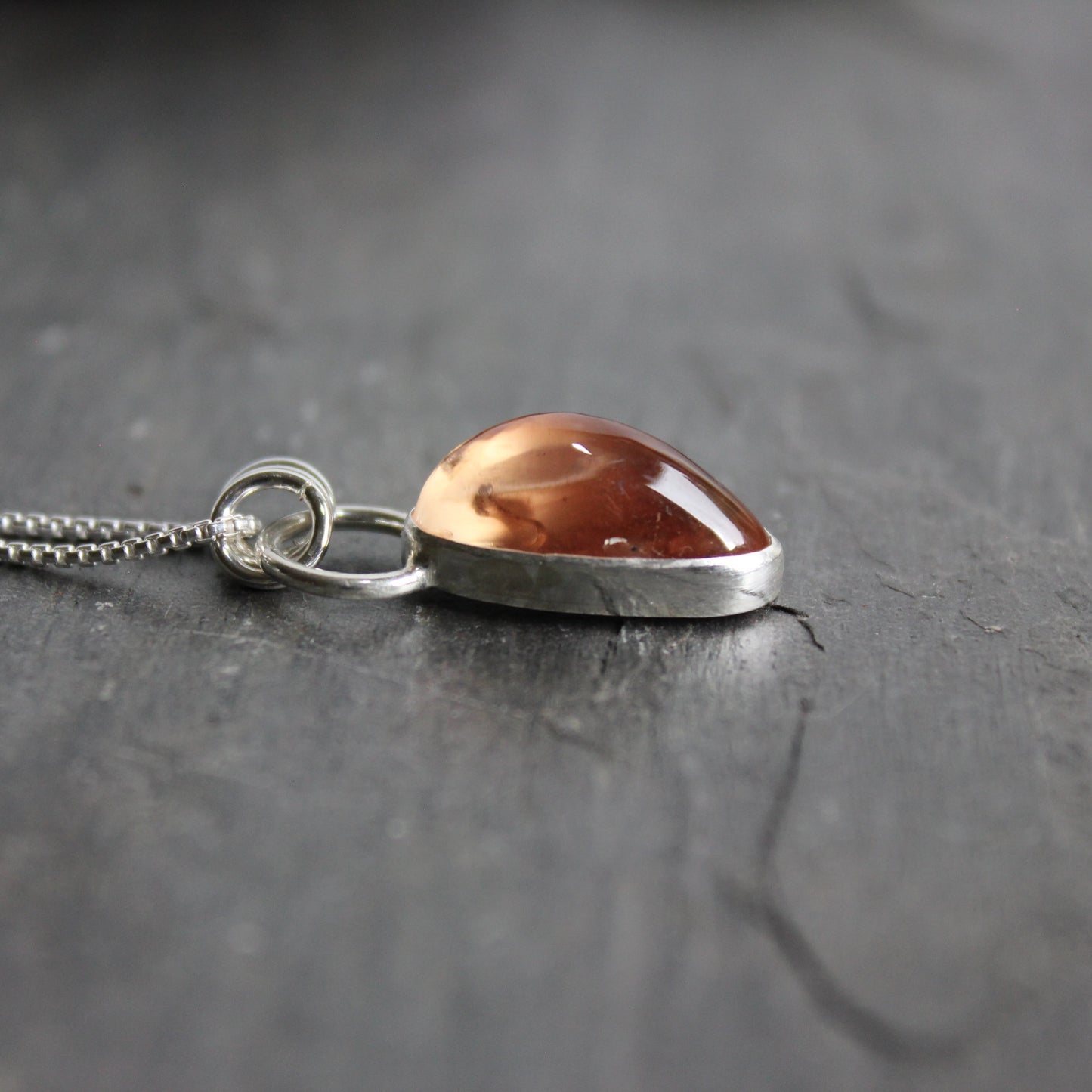 A handmade chunky oblong peach Oregon Sunstone in a sterling and fine silver bezel setting on a sterling silver chain. 