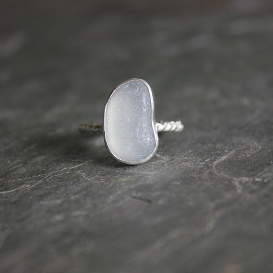 This is a piece of gray sea glass that is set in a fine and sterling silver bezel setting on a twisted wire band. Size 7 1/4