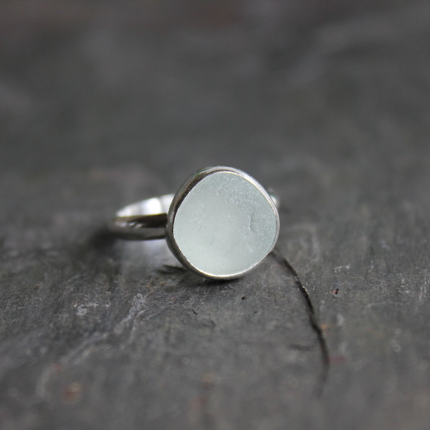 This is a chunky round piece of white sea glass set in a fine and sterling silver bezel setting with a hammered silver band.  Size 8 1/4