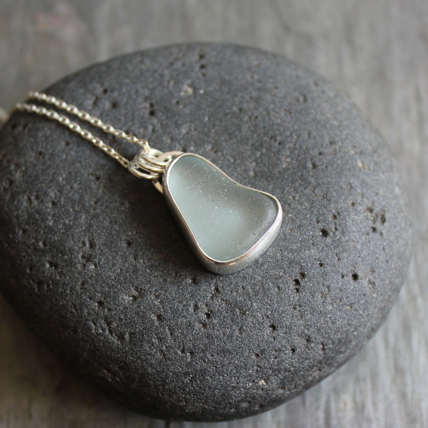 This pendant has a chunky piece of gray sea glass and it is set in a fine and sterling silver bezel setting with an 18" chain.