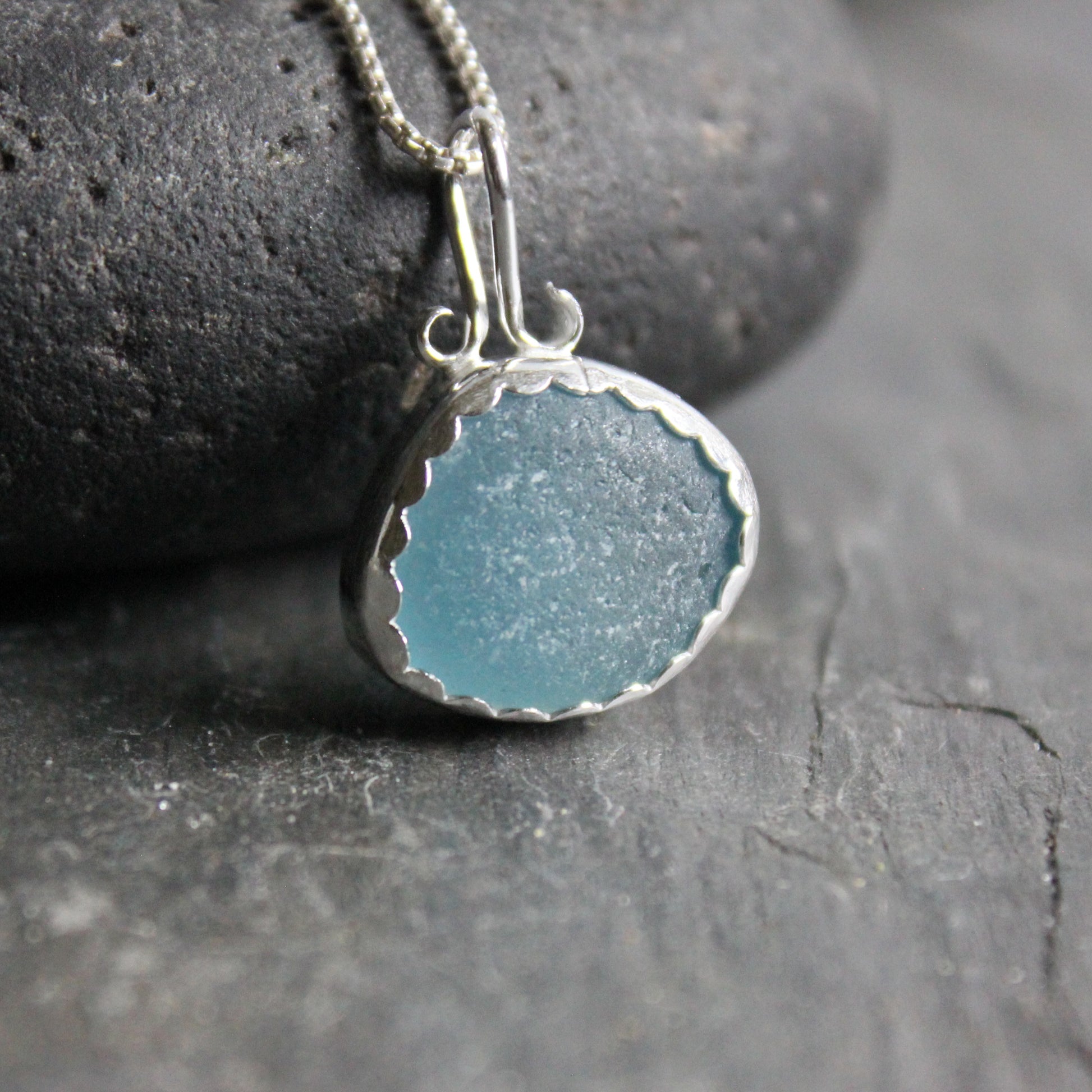 This is a large piece of teal sea glass set in a fine and sterling silver scalloped bezel setting with a fancy bail. 