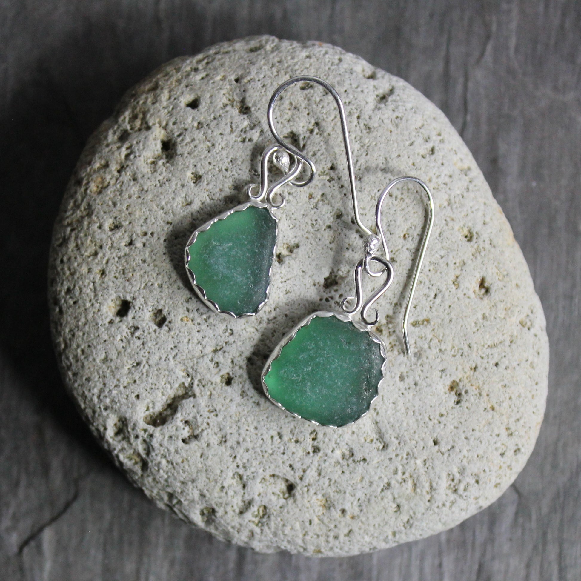 Dark green dangly sea glass earrings made with a sterling and fine silver scalloped bezel setting and a fancy bail on sterling silver ear wires. 