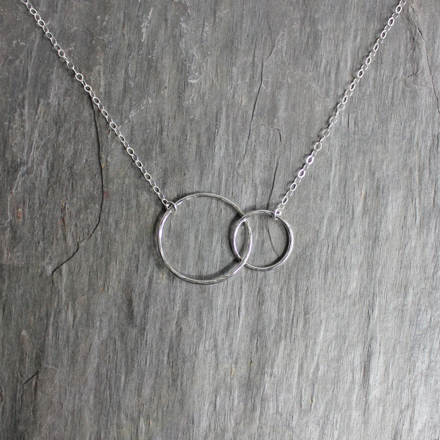 A one inch hammered circle and a 1/2 inch hammered circle interlocking and attached to sterling silver chain to make a elegant necklace.