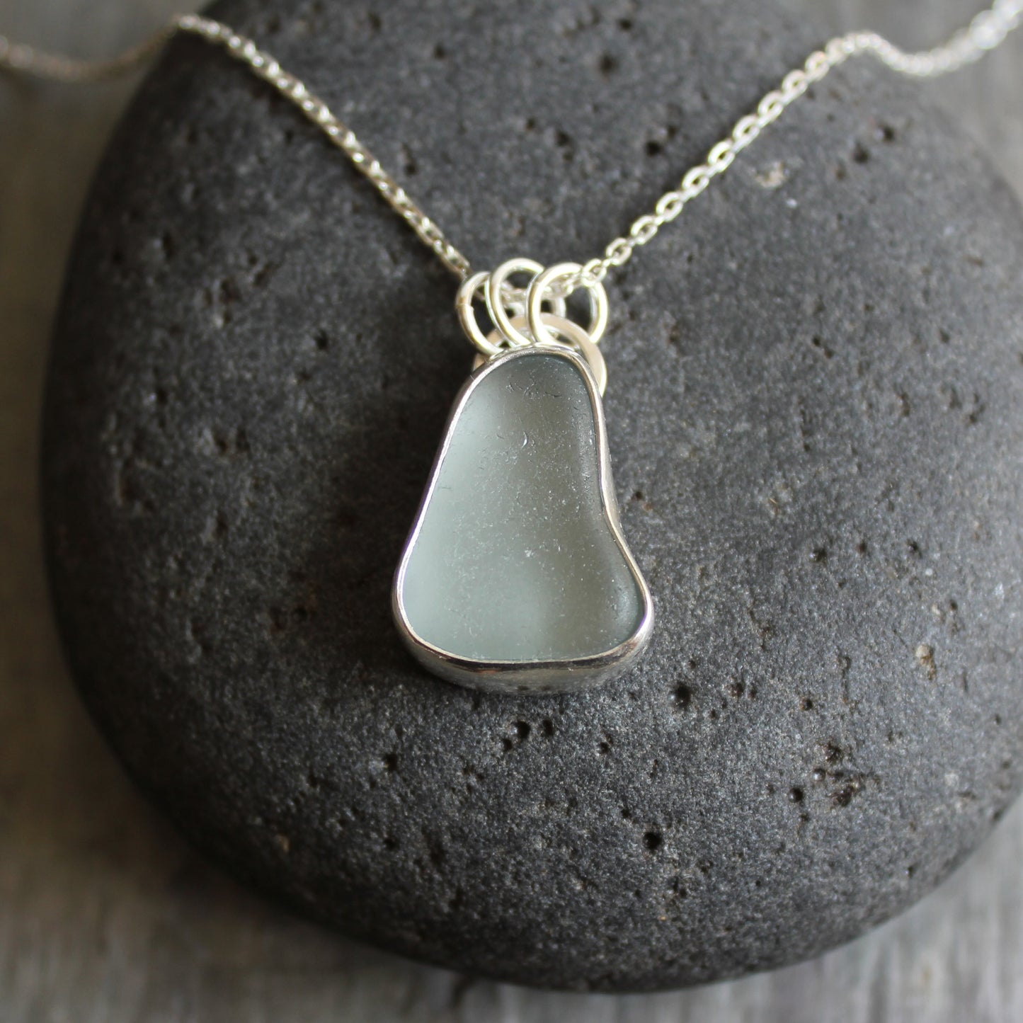 This pendant has a chunky piece of gray sea glass and it is set in a fine and sterling silver bezel setting with an 18" chain.