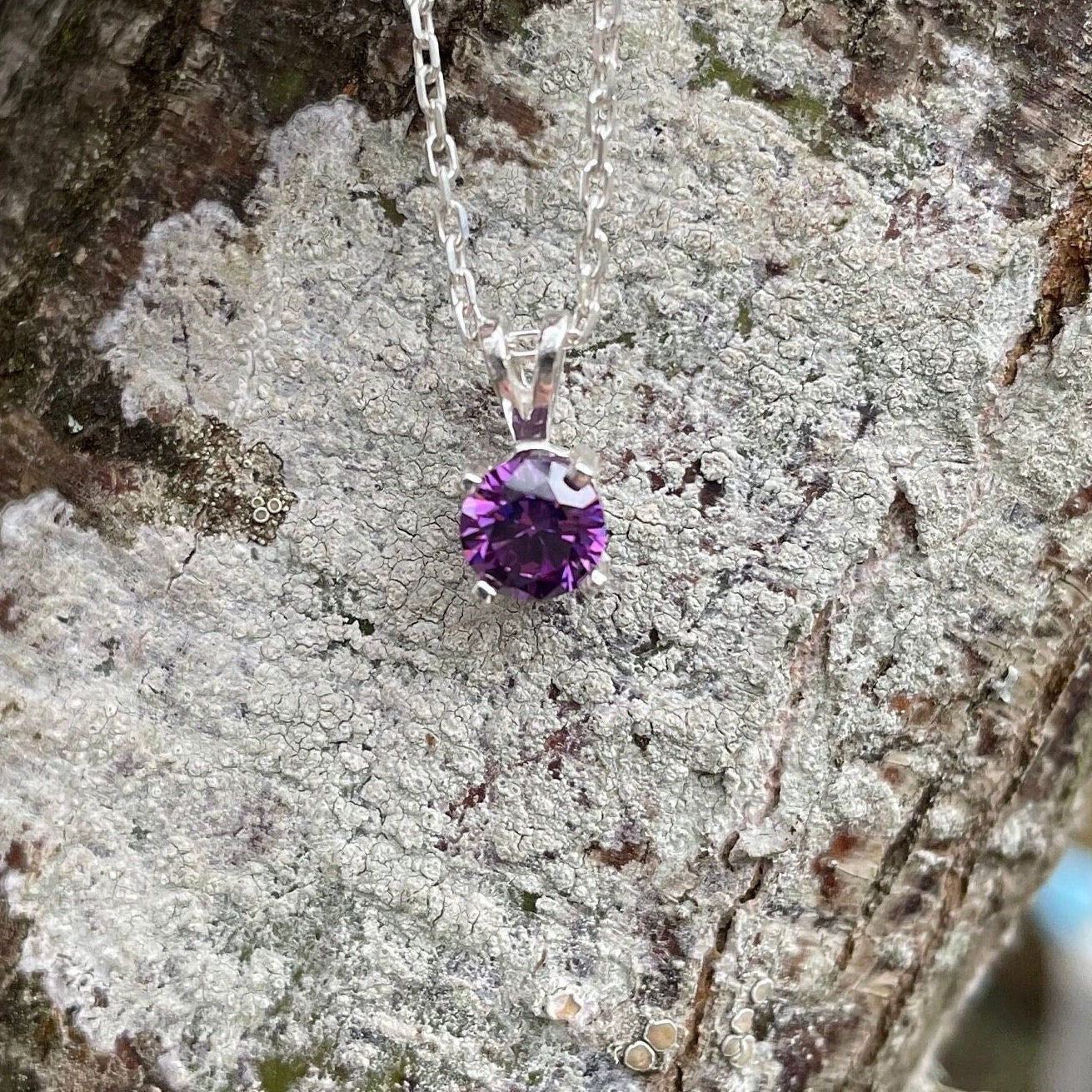 This necklace has a 6mm round faceted synthetic amethyst set in a 4-prong sterling silver setting on a sterling silver chain.