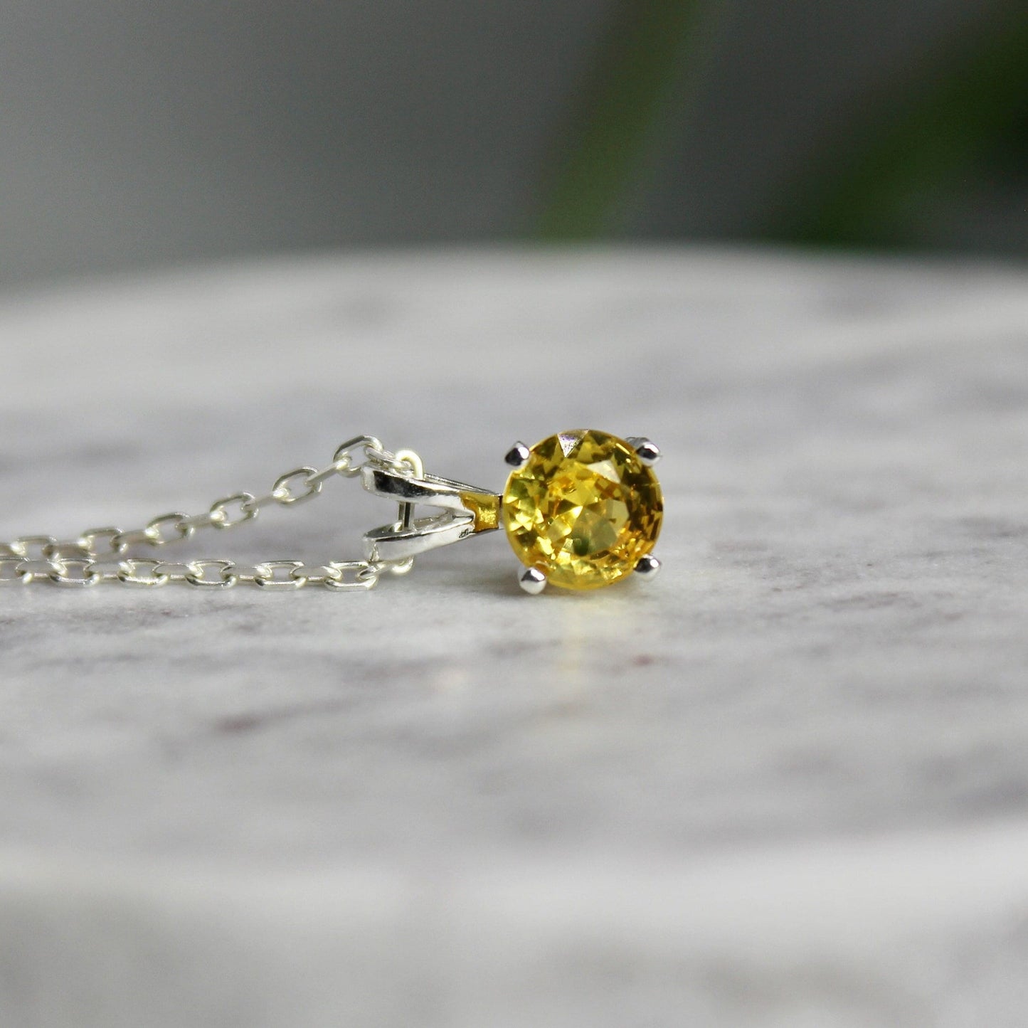 This necklace has a 6mm round faceted lab created golden yellow topaz that is set in a sterling silver 4-prong pendant setting on a sterling silver chain.