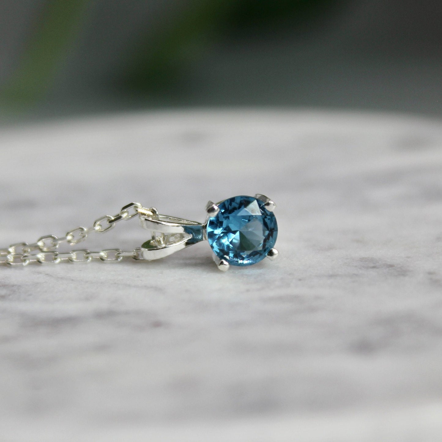 This necklace has a 6mm round faceted blue zircon set in a 4-prong sterling silver pendant with a sterling silver chain.
