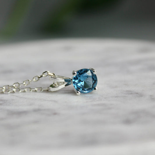 This necklace has a 6mm round faceted blue zircon set in a 4-prong sterling silver pendant with a sterling silver chain.