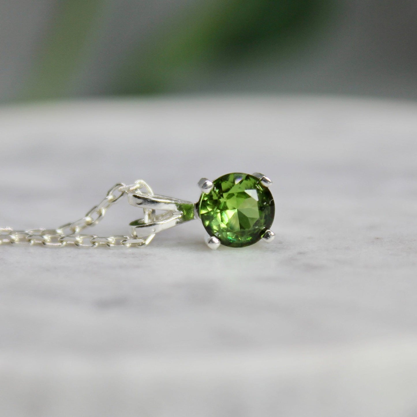 This necklace has a 6mm round faceted lab created peridot set in a sterling silver 4-prong pendant setting on a sterling silver chain.