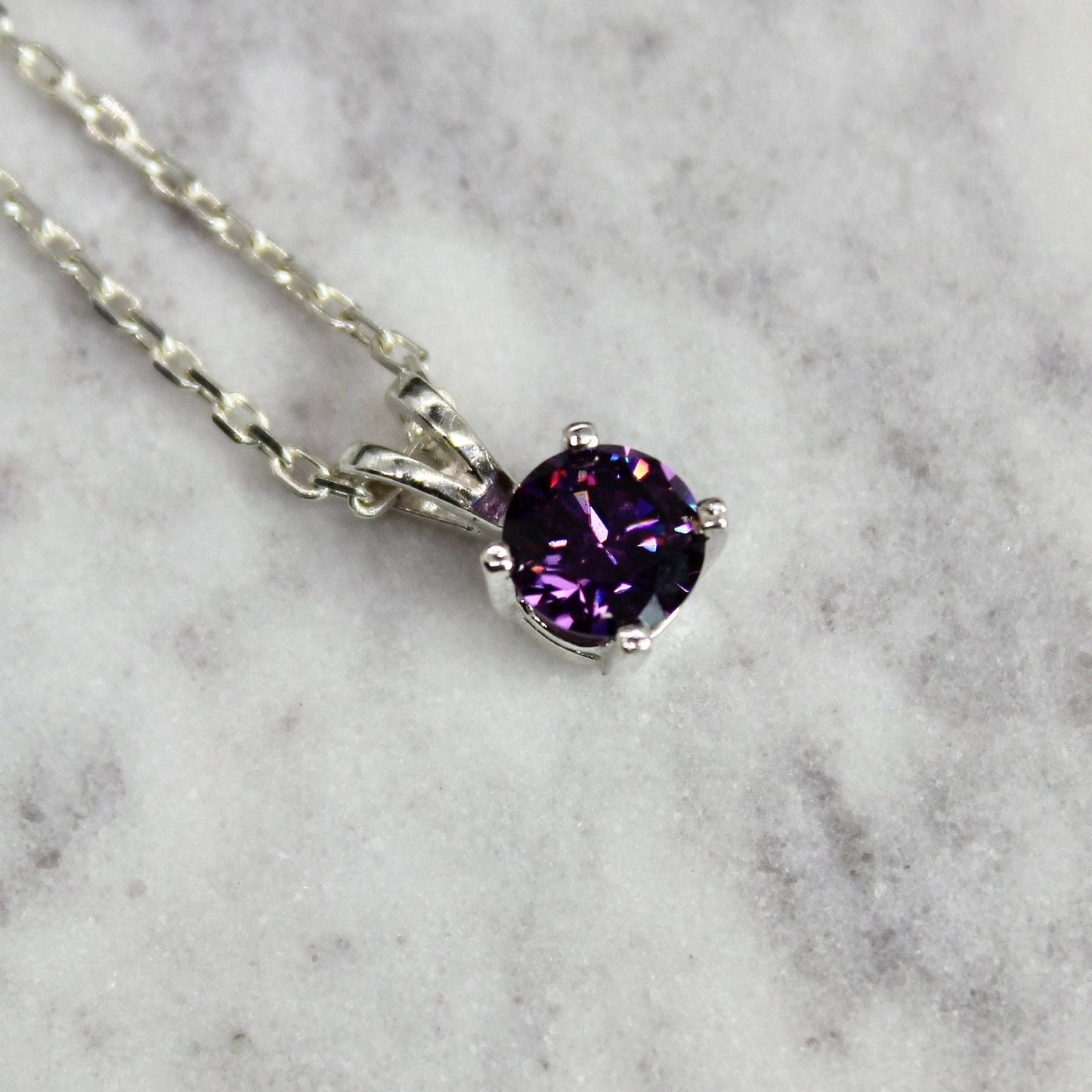 This necklace has a 6mm round faceted synthetic amethyst set in a 4-prong sterling silver setting on a sterling silver chain.