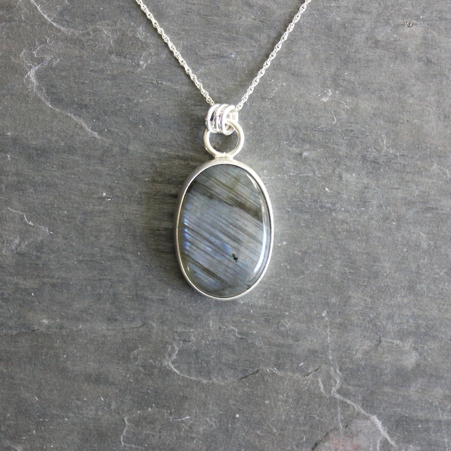 Necklace with an oval pendant on a gray stone background