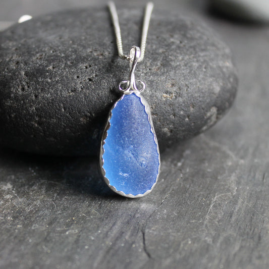 This is a large chunky piece of rare blue sea glass from Martinique and it is set in a fine and sterling silver scalloped bezel setting with a fancy bail.  