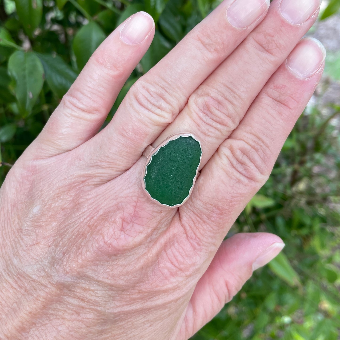 This is a large chunky piece of European dark emerald green sea glass that is set in a fine & sterling silver scalloped bezel setting and on a sturdy silver band.  Size 10 1/2 modeled on a hand.